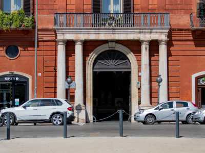 Al centro del piano inferiore (occupato da alcuni esercizi commerciali) si apre il portale d�ingresso con un arco a tutto sesto realizzato in pietra bianca...